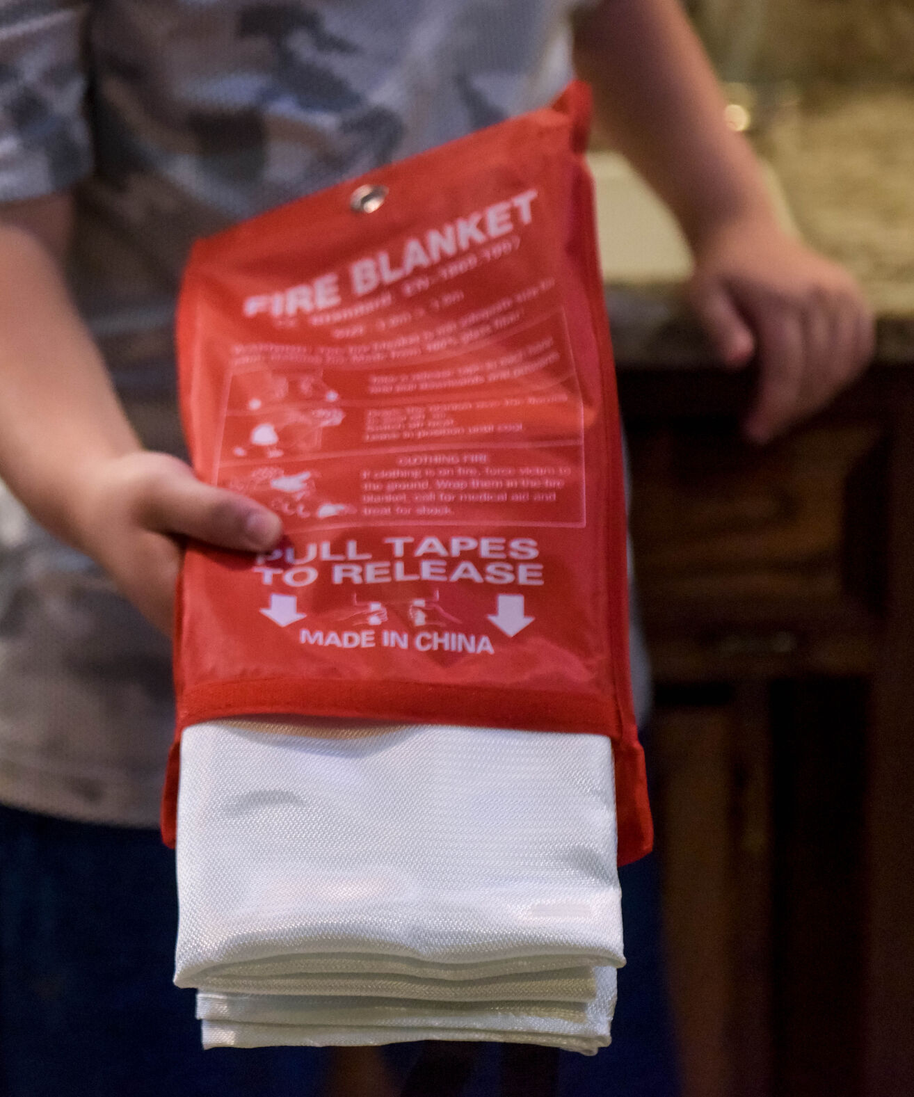 Caleb Ortbals 11, holds out a fire safety blanket to show his younger brother
